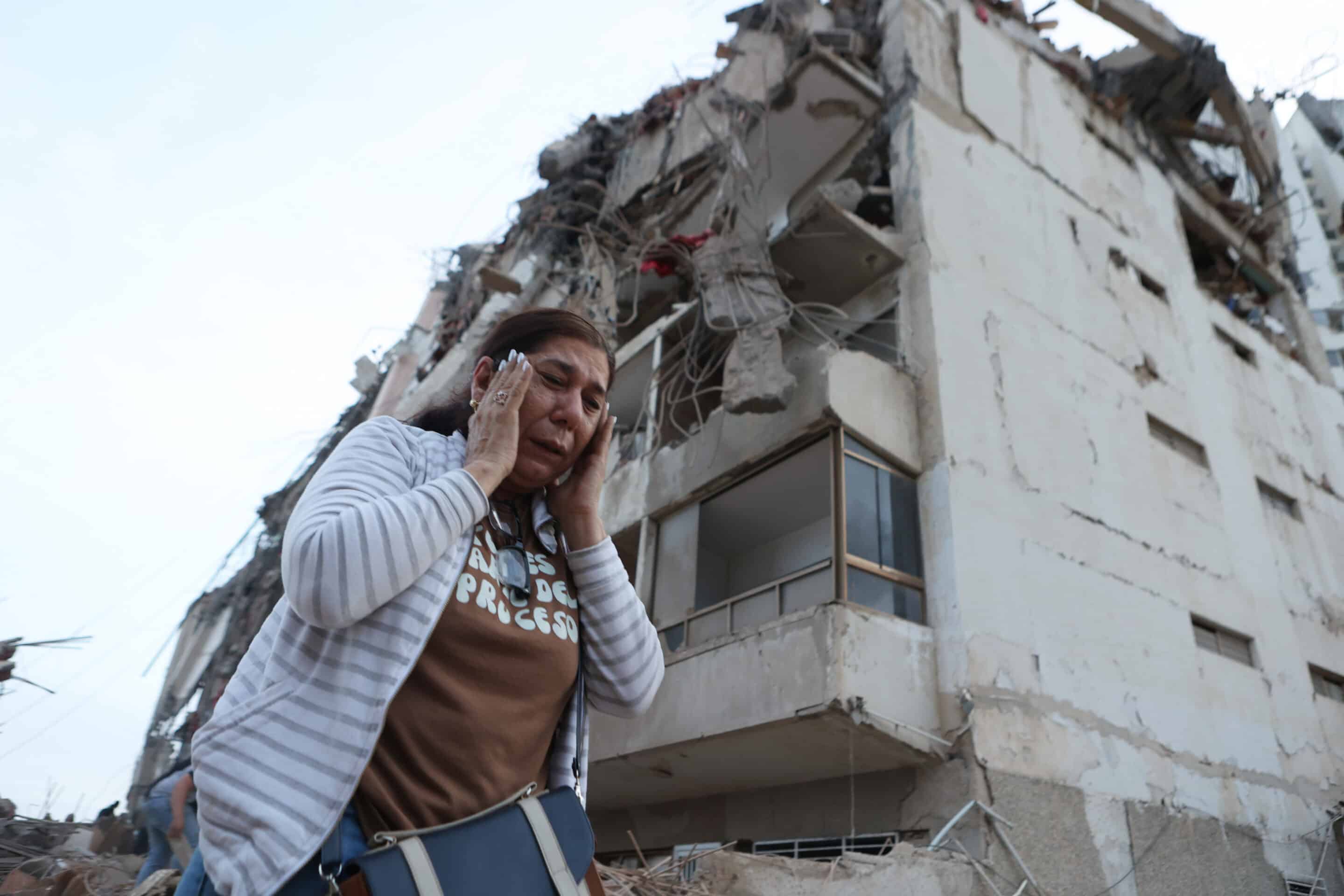A woman walks past a building damaged during an earthquake in La Guaira, Venezuela, Thursday, June 25, 2026. (AP Photo/Pedro Mattey)