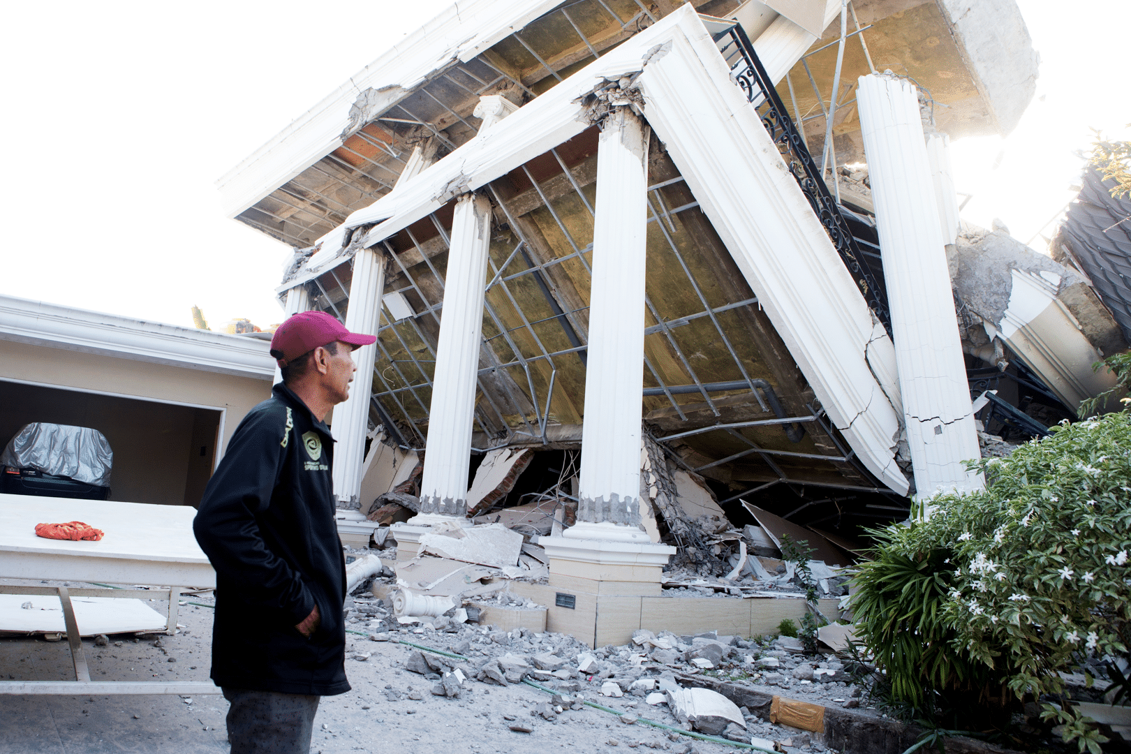 A man examines a building that collapsed during an earthquake in Reo, East Nusa Tenggara province, Indonesia, Monday, Aug. 17, 2026. (AP Photo/Firdia Lisnawati)